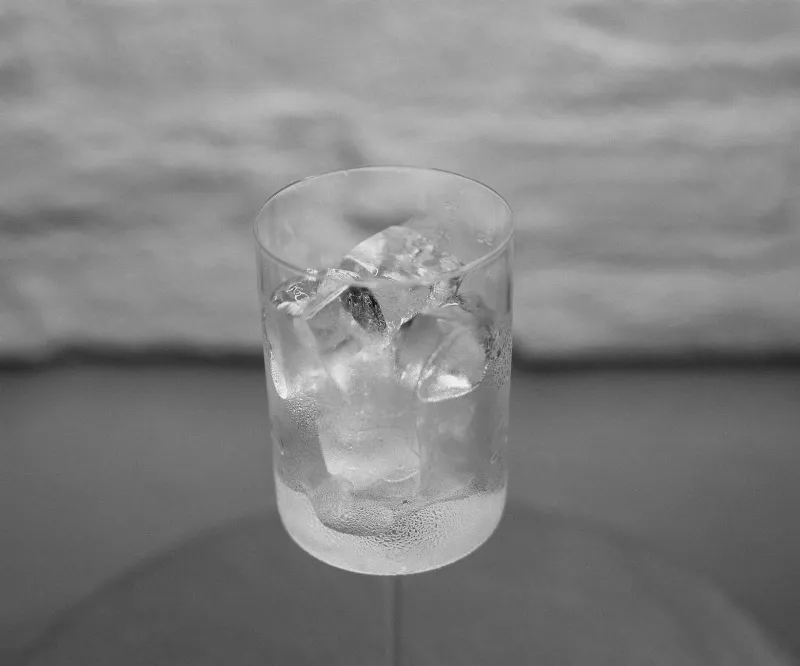 A close-up of colorful ice cubes melting in a clear glass of sparkling water, showcasing vibrant colors and the interaction between the ice and liquid.