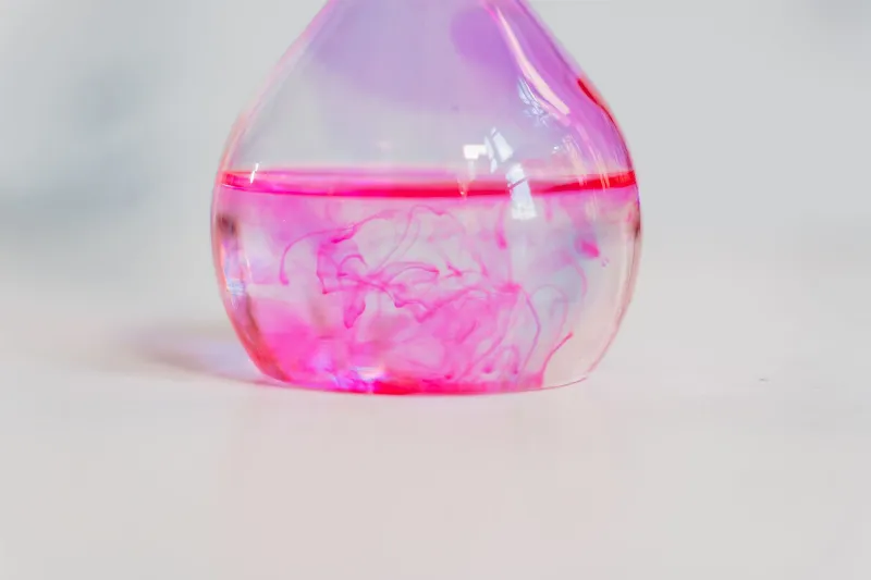 Un gros plan d'une réaction pétillante colorée avec des couleurs vives se mélangeant dans un récipient transparent, mettant en évidence le mouvement dynamique des bulles.